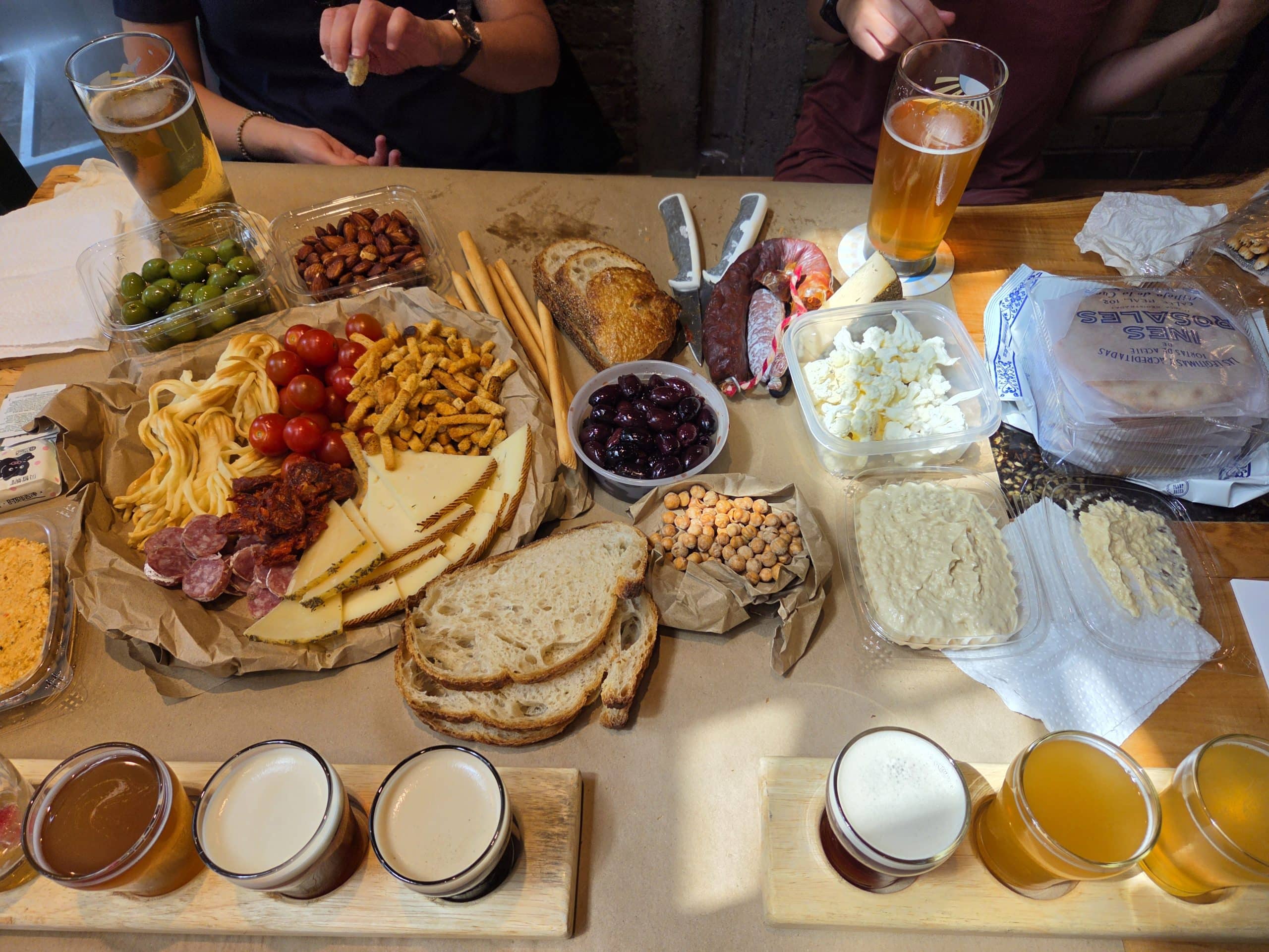 Flights of beer and market food spread out on a table at brewing at the market